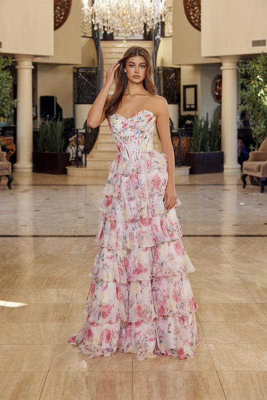 Elevate your prom night with the Nox Anabel Q1779, a stunning strapless gown that commands attention. This architectural masterpiece features a pleated sweetheart neckline and structured corset bodice that flatters and supports. Delicate ruffle detailing cascades down the silhouette, while an enchanting floral print adds romantic dimension. The backless design creates an alluring statement, and a graceful train completes the look with timeless elegance. Perfect for those seeking a dress that balances bold s