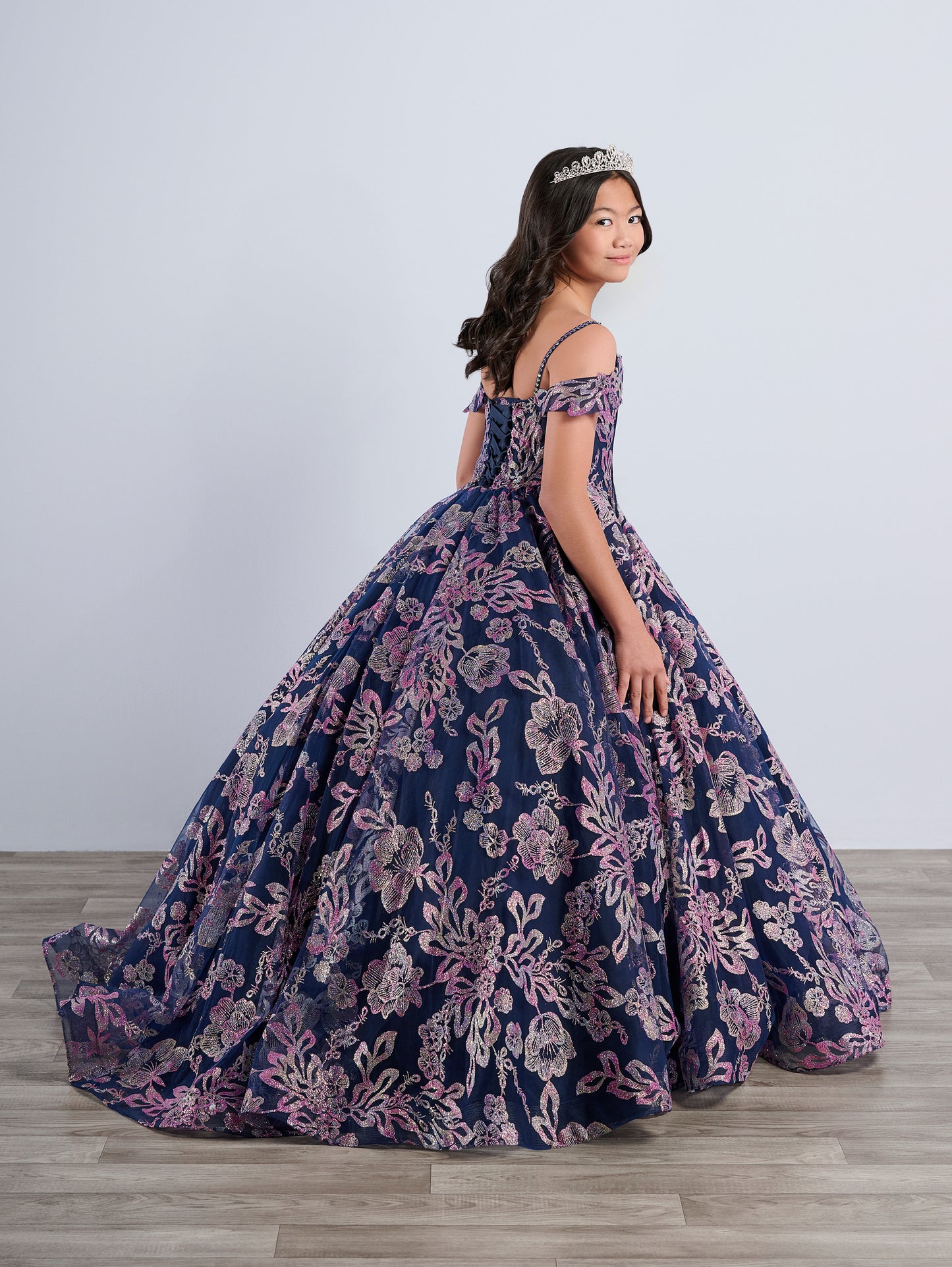 Be the belle of the ball in the Tiffany Princess 13794 Glitter Floral Girls Pageant Dress. This stunning off the shoulder ballgown features a corset bodice and a flowing cape for added drama. The glittering floral details will make you stand out from the crowd. Perfect for any pageant or special occasion.
Sizes: 2-16
Colors: Navy/Multi, Pink/Multi