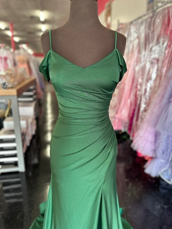 The Nina Canacci 1578 gown is a masterful blend of elegance and modern design. Crafted from fitted emerald jersey fabric, it contours the body with precision. The off-the-shoulder neckline highlights the collarbone, while the ruched detailing adds texture and sophistication. A slit enhances mobility and allure, complemented by a graceful train that elevates the gown’s formal appeal. Ideal for upscale events, this dress combines comfort with striking style for a confident, polished look.
Size: 4
Color: Eme