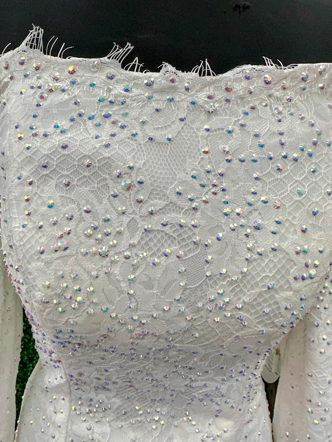 This exquisite Johnathan Kayne gown in size 4 features a long, fitted silhouette crafted from delicate white lace. Designed with an off-the-shoulder neckline and long sleeves ending in elegant ruffle cuffs, it offers a refined and sophisticated look. The dress is adorned with AB crystals that add subtle sparkle, while the eyelash lace edges and flowing train enhance its graceful presence, making it an ideal choice for pageants or formal events.
Size: 4
Color: White