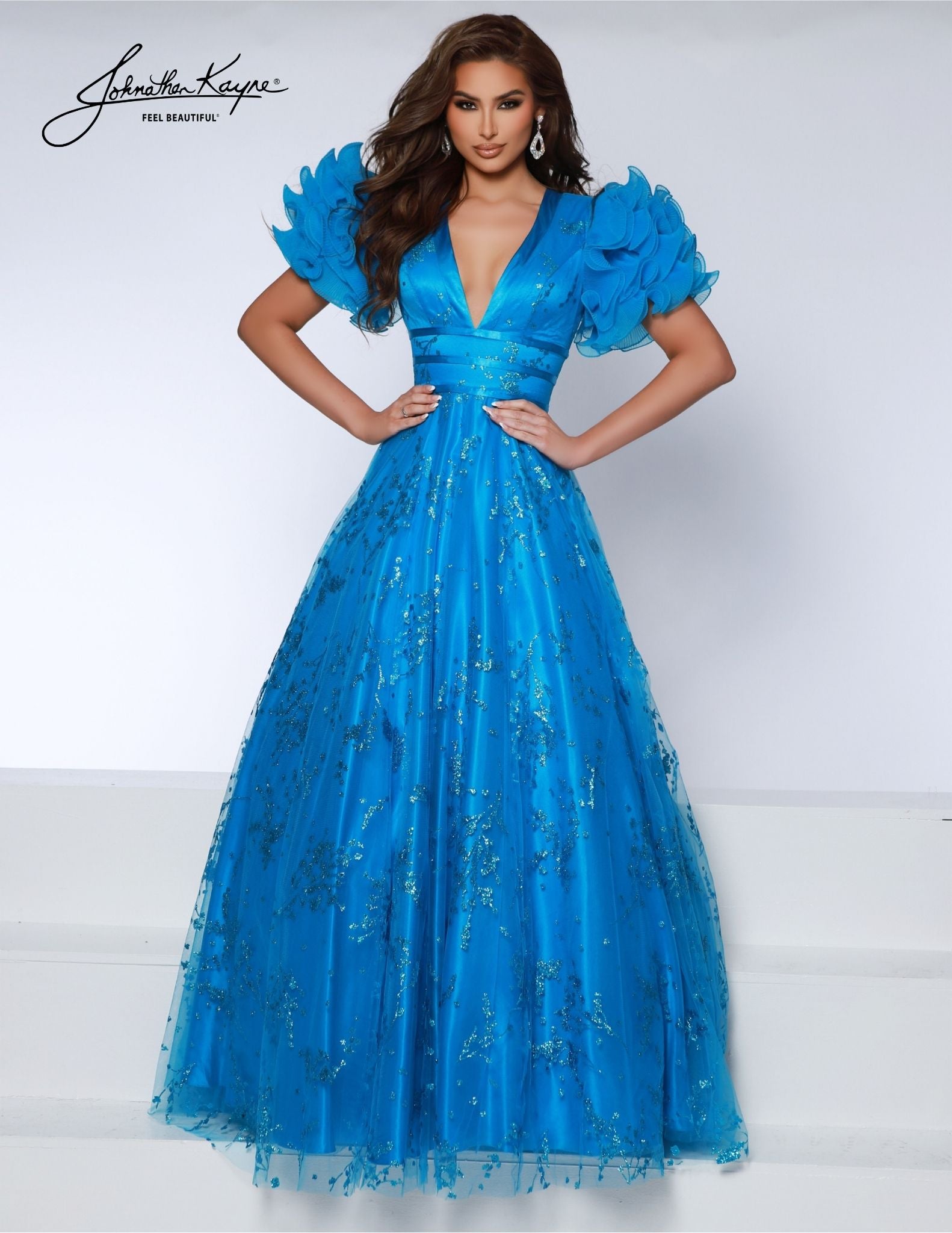 Capture attention at any formal event in the Johnathan Kayne 2841 dress. Crafted with an A- Line bodice, intricate puff sleeves, and full tulle skirt, this glamorous ballgown is an eye-catching choice for pageants and proms alike. An open back adds to the allure, making it a memorable statement piece. Be the belle of the ball and the envy of all with our glitter ballgown.