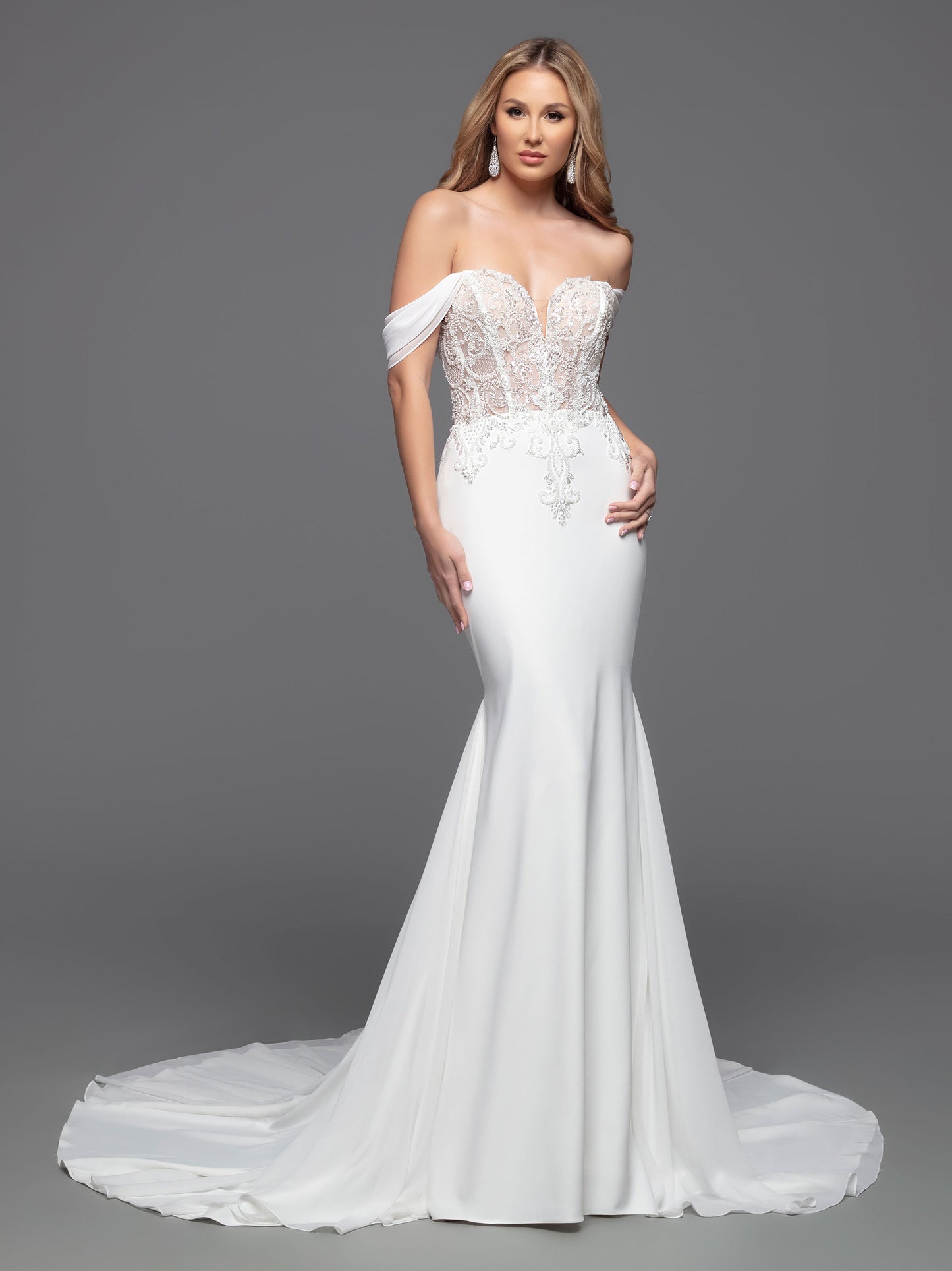 This Davinci Bridal 50803 Sheer Beaded Bodice wedding dress is a timeless choice for your special day. An elegant fit & flare silhouette with a corseted back, beaded appliques, and soft off-the-shoulder straps that flatter the neck and shoulders. The simple crepe skirt completes the classic look. Sizes: 2-20 Colors: Ivory