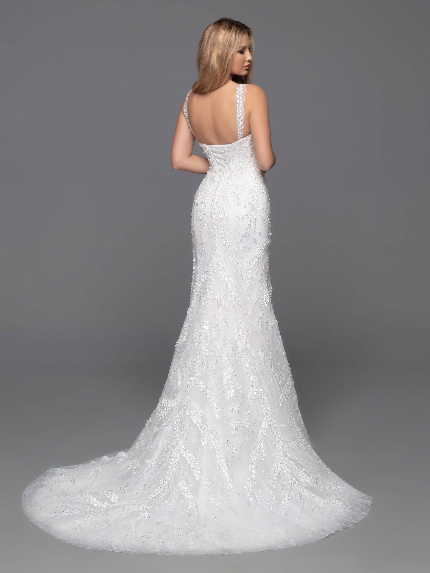 The David Bridal 50805 Draped Beaded Lace Shimmer Fitted Wedding Dress is the essence of elegance. Crafted from intricate beaded tulle and featuring sheer beaded straps and a corset back, this timeless fit and flare sheath exudes classic sophistication. Sizes: 2-20 Colors: Ivory/Blush, Ivory/Ivory