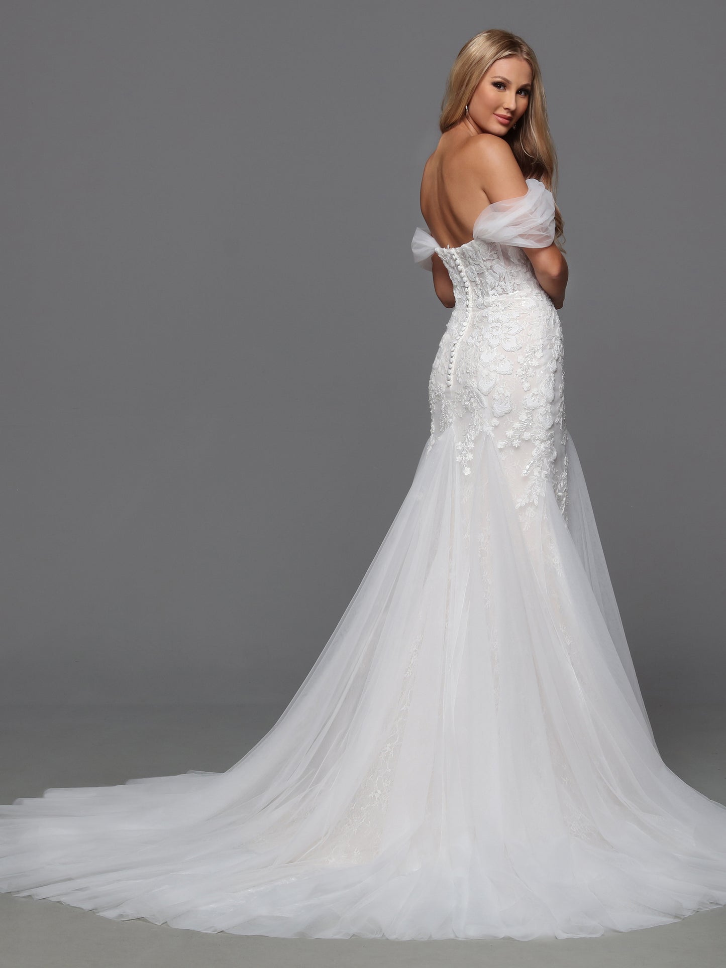 This exquisite Davinci Bridal gown features an ivory beaded lace corset that elegantly sculpts the silhouette. Designed in a flattering mermaid style, it gracefully hugs the body before flaring out, creating a timeless and sophisticated look. The off-the-shoulder neckline adds a romantic touch, perfect for a bride seeking classic elegance on her special day. Traditional with on-trend touches, this wedding dress features a sheer lace bodice and a mermaid-style skirt. The detachable off-the-shoulder straps so