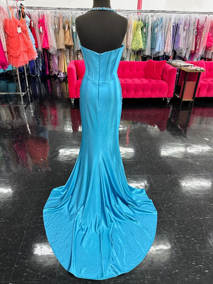 This Jovani D5091 Crystal Corset Halter Prom Dress exudes elegance and glamour. The crystal corset and halter neckline captivate attention while the slit and ruched waist add a touch of drama. Perfect for prom, pageants, or any formal event. Make a statement with this stylish and flattering gown. This enchanting floor-length gown features a figure-hugging silhouette with an alluring high slit. The sweetheart neckline is adorned with intricate embellishments that cascade down the fitted bodice. The gown is s