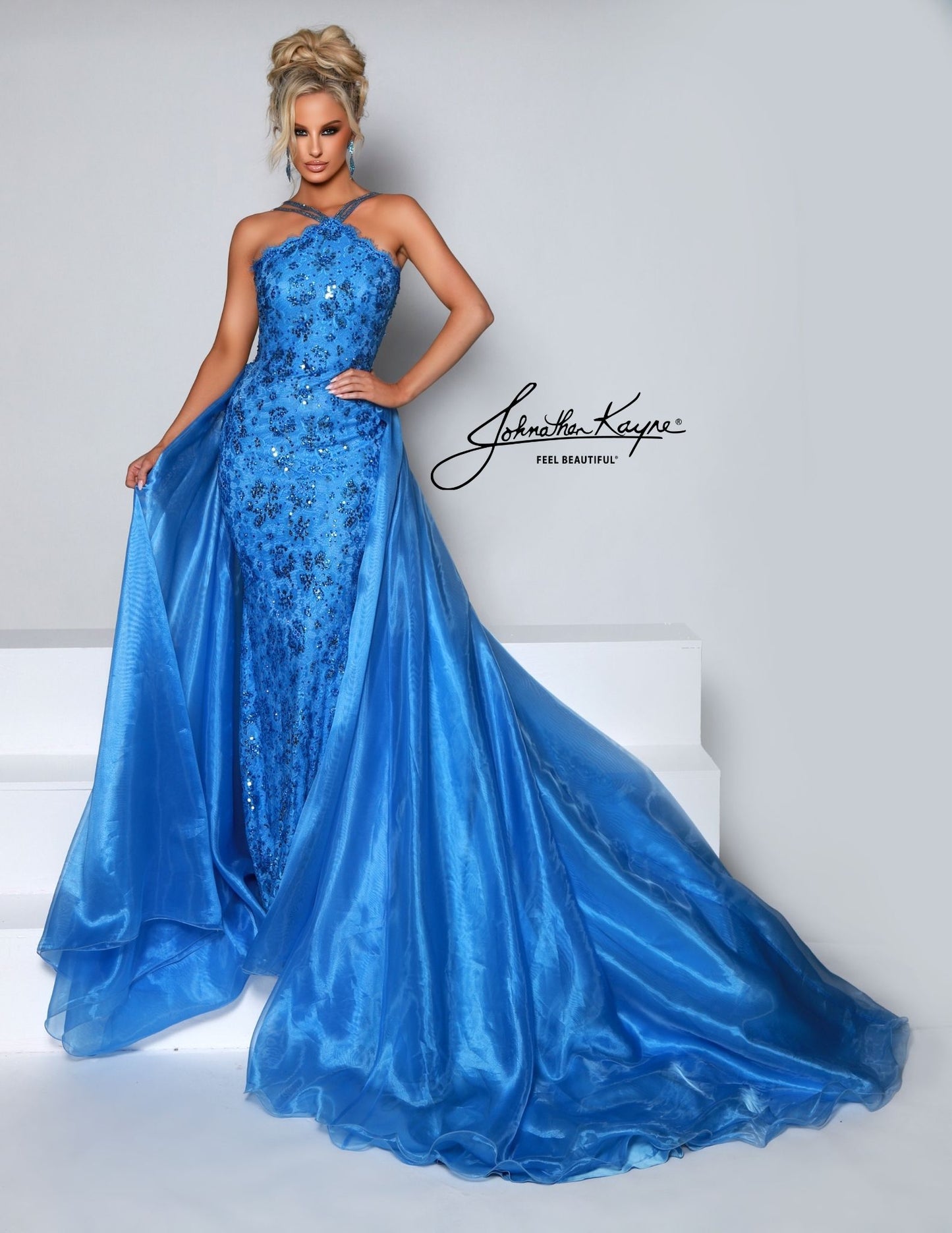 Look elegant with this Johnathan Kayne 2618 pageant dress. The high neck and sweeping long skirt are adorned with sequin lace and crystal detailing, perfect for any special occasion. Make a lasting impression. This style is sure to be a knockout at your next pageant! Walk across stage with confidence in this halter neck beaded stretch lace fitted gown with organza overskirt.