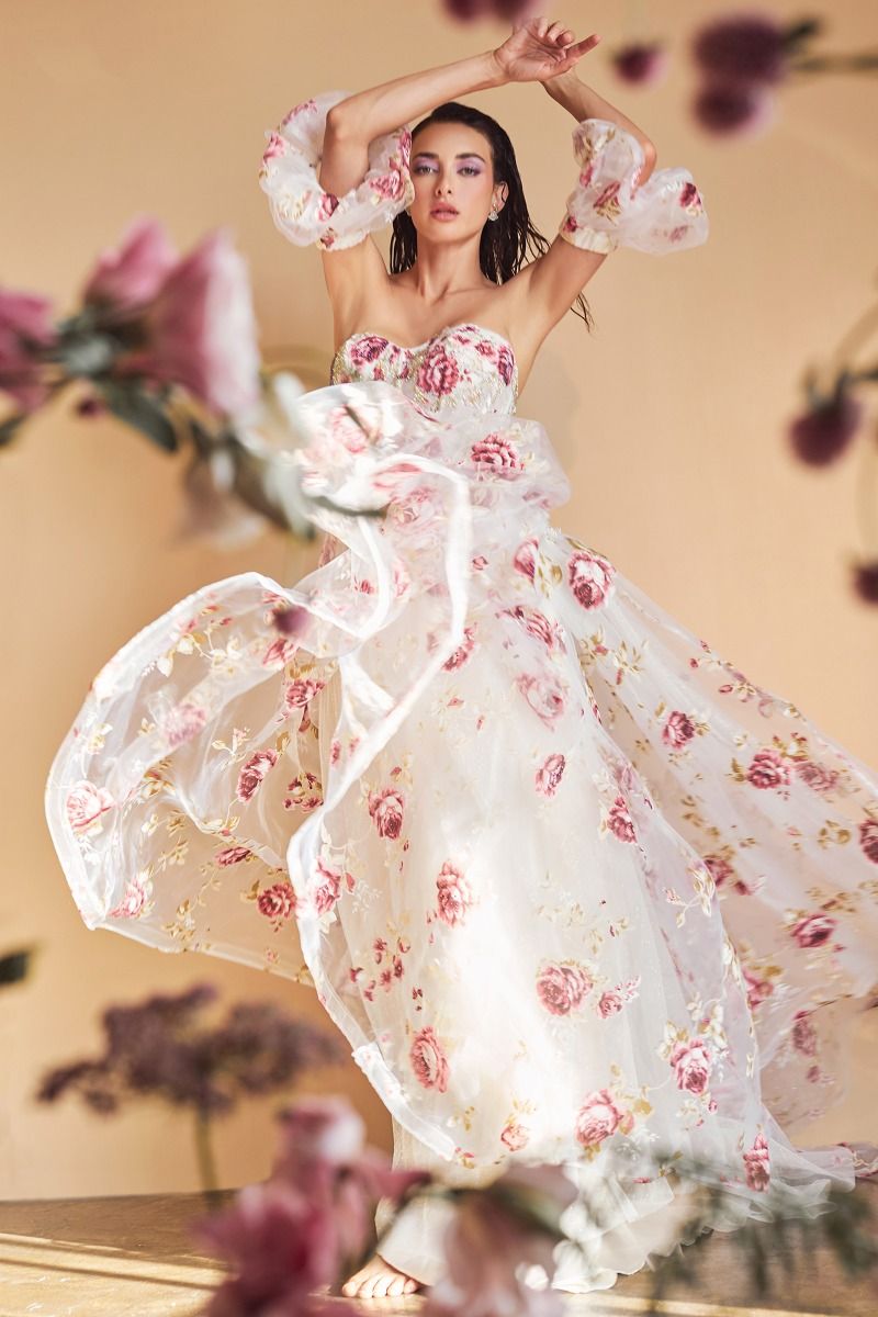 Elevate your formal attire with the Andrea & Leo Couture A1133 Floral Print A Line Prom Dress. The crystal embellished bodice adds a touch of glamour to the classic floral print, while the puff sleeves and sheer corset exude elegance. Perfect for any special occasion, this dress combines style and sophistication in one stunning design. This strapless organza peony print ball gown is a breathtaking and romantic choice for any fairytale garden.