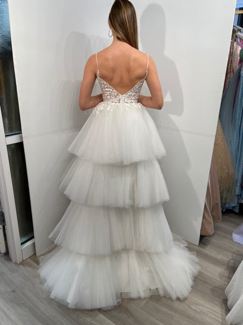 Jovani 07263 High Low Prom Dress Pageant Gown. This Jovani formal gown features a floral embroidered sheer bodice with a mesh insert plunging neckline, spaghetti straps and pleated layers of long train. Jovani 07263 High Low Prom Dress Embroidered Floral Bodice Pleated Train Layered Ruffle Lace Sheer Available Size-00-24 Available Color- Off/White, Lilac, Mint, Blush, Navy, Red, Fuchsia