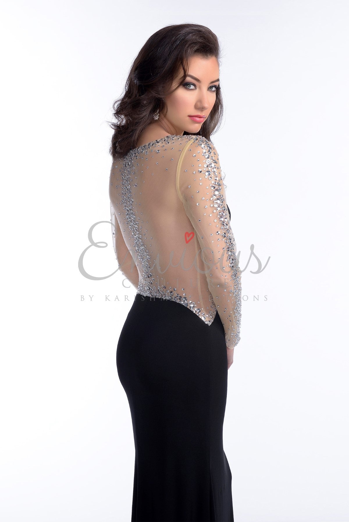 Envious Couture by Karishma Creations style 16114 is a timeless evening dress with illusion jewel neckline bodice adorned with crystals and has long sheer sleeves embellished with scattered crystal accents. This stunning sweetheart style is made of jersey material to showcase your curves.