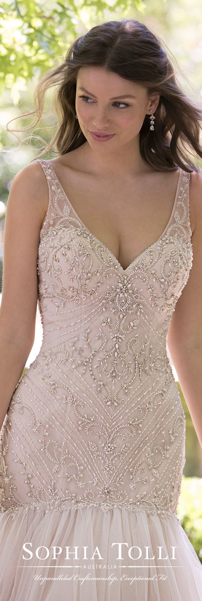 Sophia Tolli Y21811 KYANITE This Sophia Tolli Y 21811 Kyanite trumpet-style wedding gown has an intricately beaded bodice, with illusion straps edging the V-neckline and open scoop back. The gathered tulle skirt begins on the drop waist, and flows to a beaded horsehair hem and chapel train. Diamante buttons trim the back zipper closure.