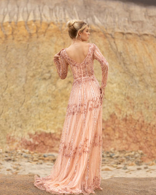 Primavera Couture 3685 This long beaded evening gown has a bateau neckline and long embellished sleeves. The A line design is beaded to the floor and has a boho tone. Available colors: Champagne, Black Multi Available sizes: 0-24