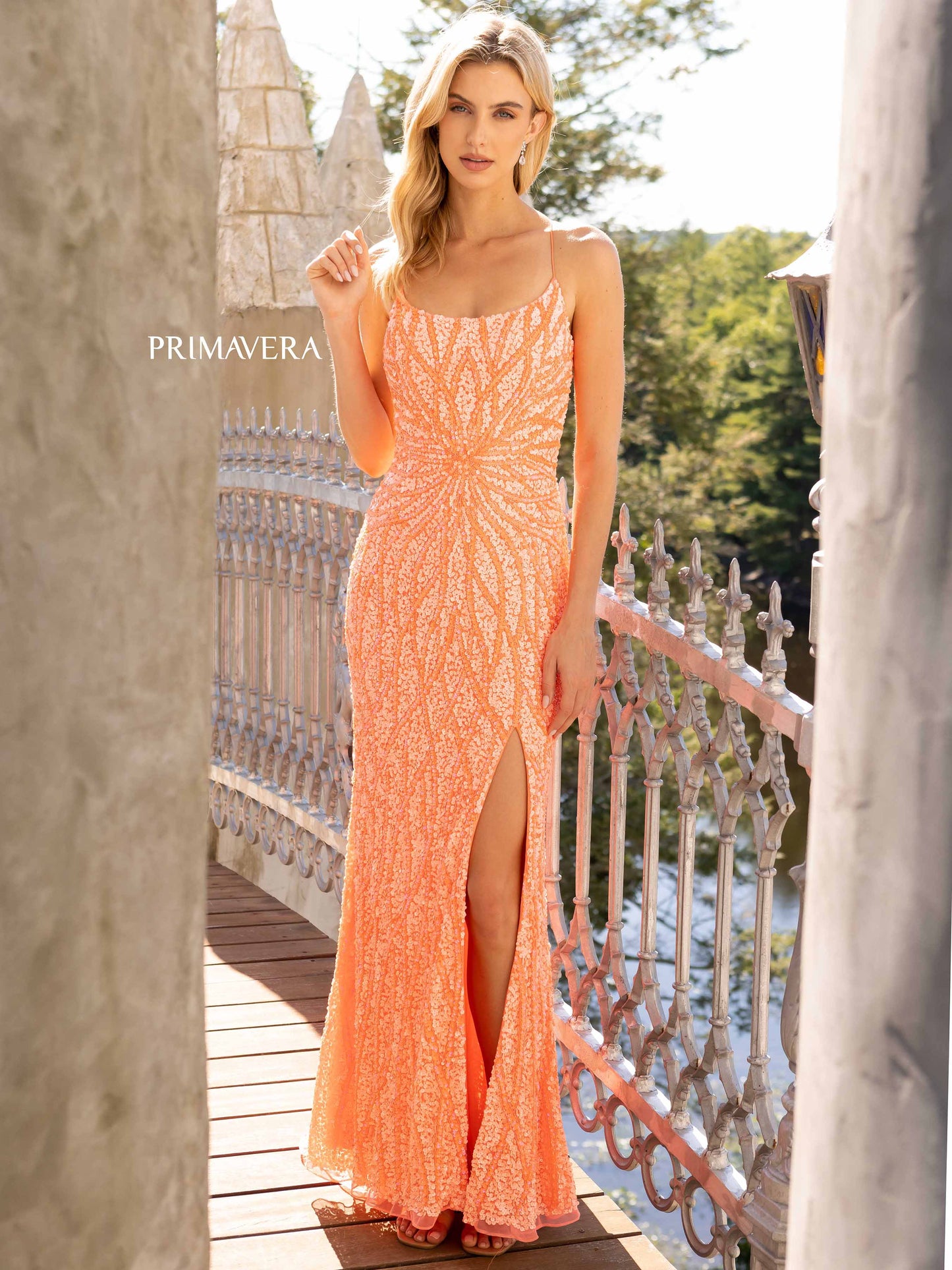 Primavera Couture 3959 This is a coral fully sequined prom dress. It features a starburst in the front of the dress with waterfall streaming sequins up and down the long length of the dress. It has a corset open back and a side slit, Available Size: 2, 10 Available Colors: Coral