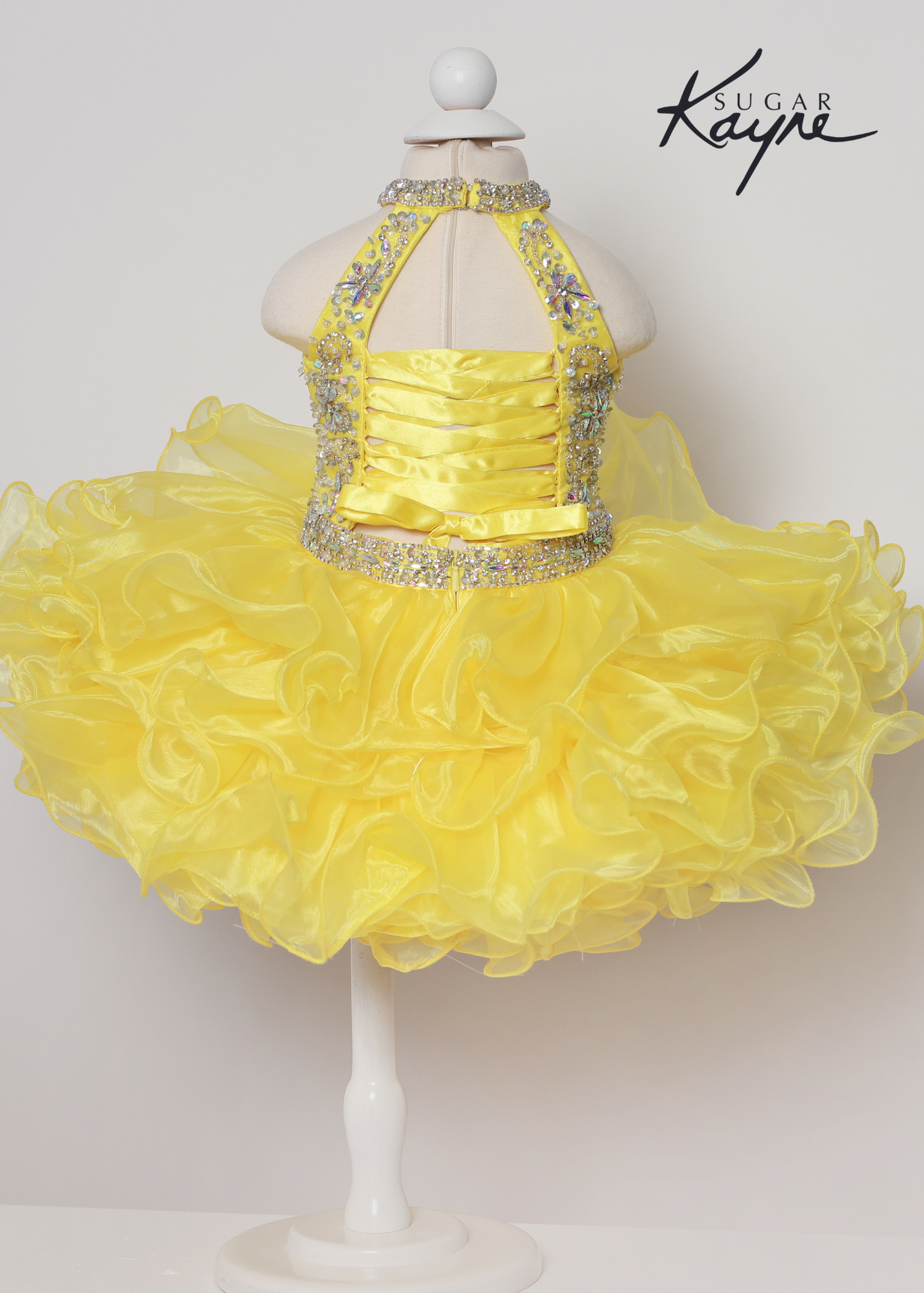 Sugar Kayne C223 Girls Baby Short ruffle Cupcake Pageant Dress Bow Halter Beaded Gown Have your little cupcake bring on all the charm in this stunning organza gown. The corset back is the perfect addition as the little one grows! Colors: Aqua, Petal Pink, Yellow Sizes: 0M, 12M, 18M, 24M, 2T, 3T, 4T, 5T, 6M, 6T Fabric Organza, Satin Lining