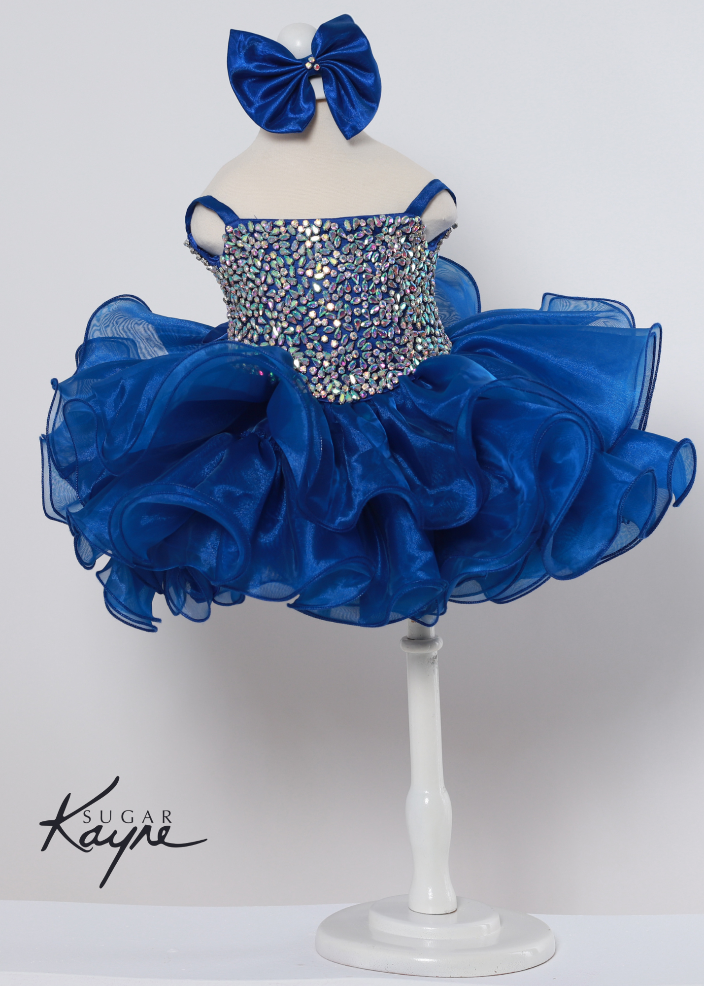 Add a touch of sparkle to your special occasion with the Sugar Kayne C226 Dress. It features intricate rhinestones and a corseted back for adjustable comfort, making it the perfect pageant gown for growing kids. The unique organza ruffles bring a delightful finish for a truly stunning look. Sizes: 0M, 12M, 18M, 24M, 2T, 3T, 4T, 5T, 6M, 6T Colors: Barbie Pink, Kiwi, Royal