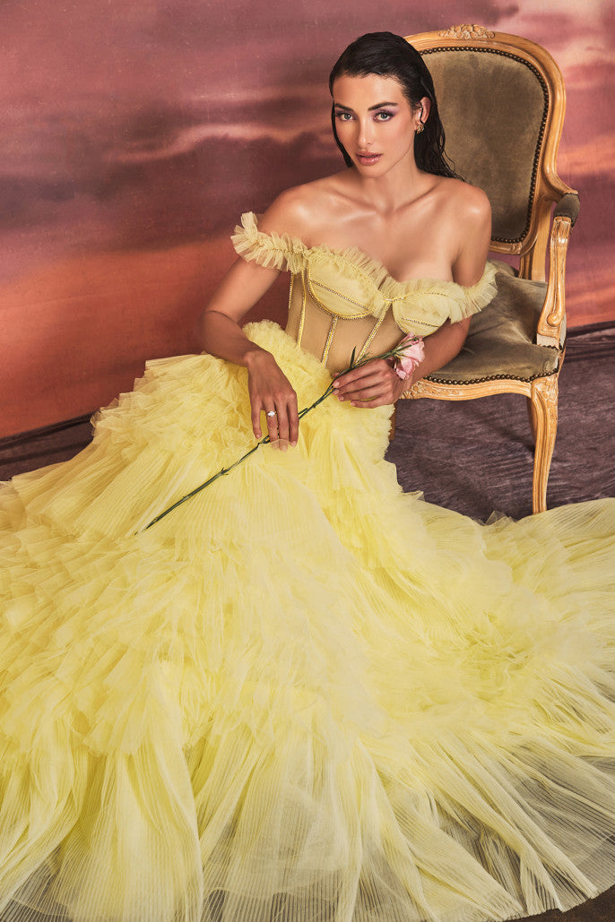 The Andrea & Leo Couture 1150 Long off The Shoulder Pleated Ruffle Ballgown Sheer Prom Dress is perfect for making a magical entrance. It features a boned, sheer bodice adorned with delicate rhinestones, ruffles and an eye-catching corset lace-up back. The elegant pleated ruffle skirt and off the shoulder sleeves provide added drama, while the corset style helps ensure a perfect fit. Sizes: 2-14 Colors: Blue, Mauve, Yellow