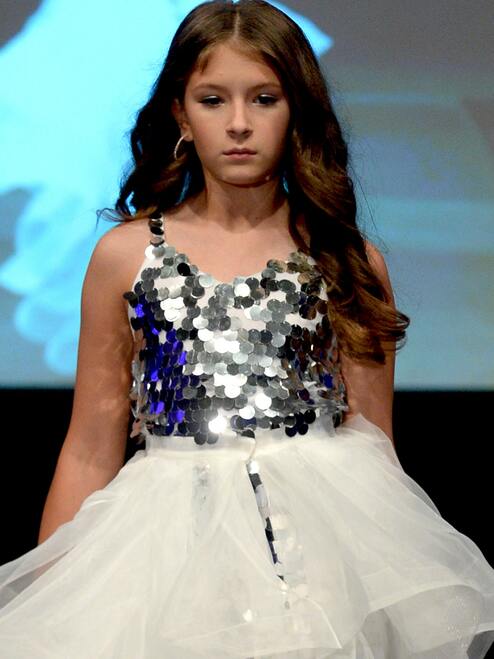 Marc Defang 5002 High Low Sequin Girls Pageant Romper Layered Detachable Overskirt Fun fashion romper Detachable Overskirt (Price inclusive of the overskirt) Large circle shape beads, Fully beaded romper Ruffled detachable skirt Center back invisible zipper Lined top Available Sizes: 4-14 Available Colors: Silver