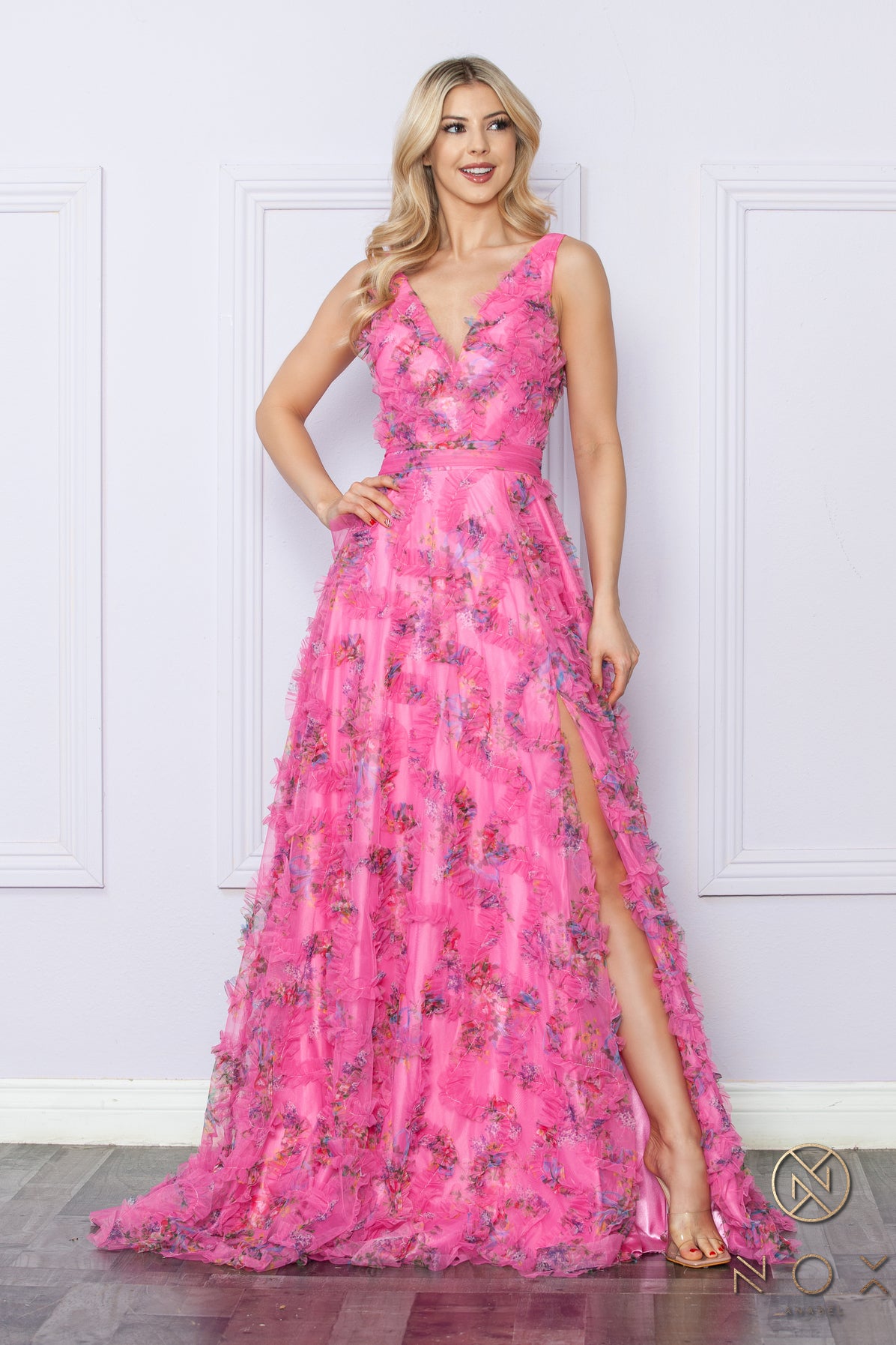 Elevate your formal ensemble with our Nox Anabel E1445 long floral A line dress. Featuring a stunning ruffle detailing and a flattering V neck, this dress is perfect for any prom or formal event. The elegant pleated design and maxi slit add a touch of boho flair to this timeless piece.  Sizes: 2-16  Colors: Blue, Fuchsia, Lilac