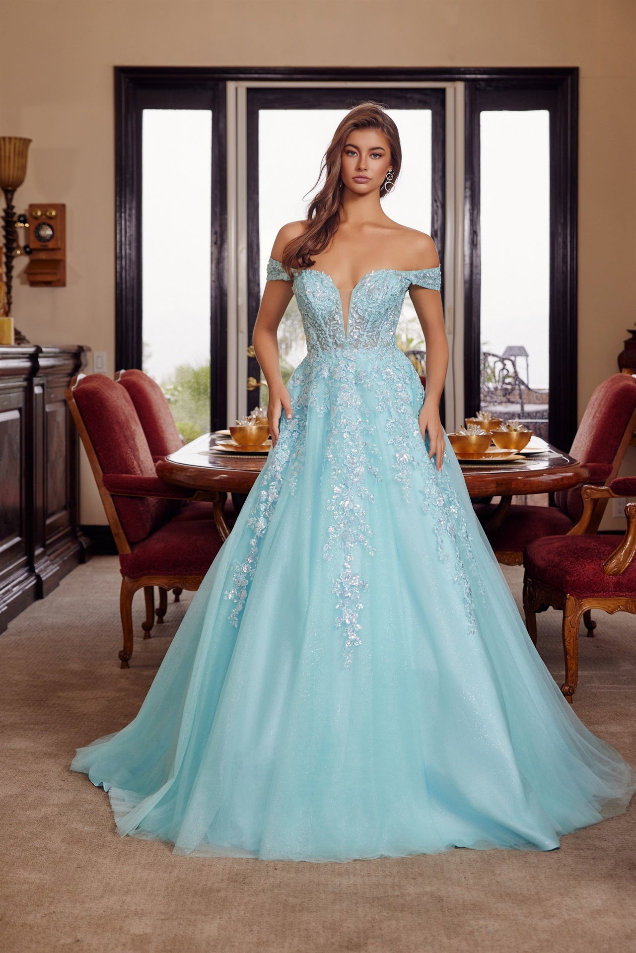 Nox Anabel's H1881 prom dress combines timeless elegance with contemporary allure. The off-the-shoulder silhouette frames the shoulders beautifully, while the sheer corset bodice creates a striking focal point with its plunging V-neckline. The flowing A-line skirt transitions into a graceful train, offering movement and drama on the dance floor. Crafted for those seeking a show-stopping entrance at prom or formal events, this dress balances sophistication with bold design details.

Sizes: 00-16

Colors: Aqu