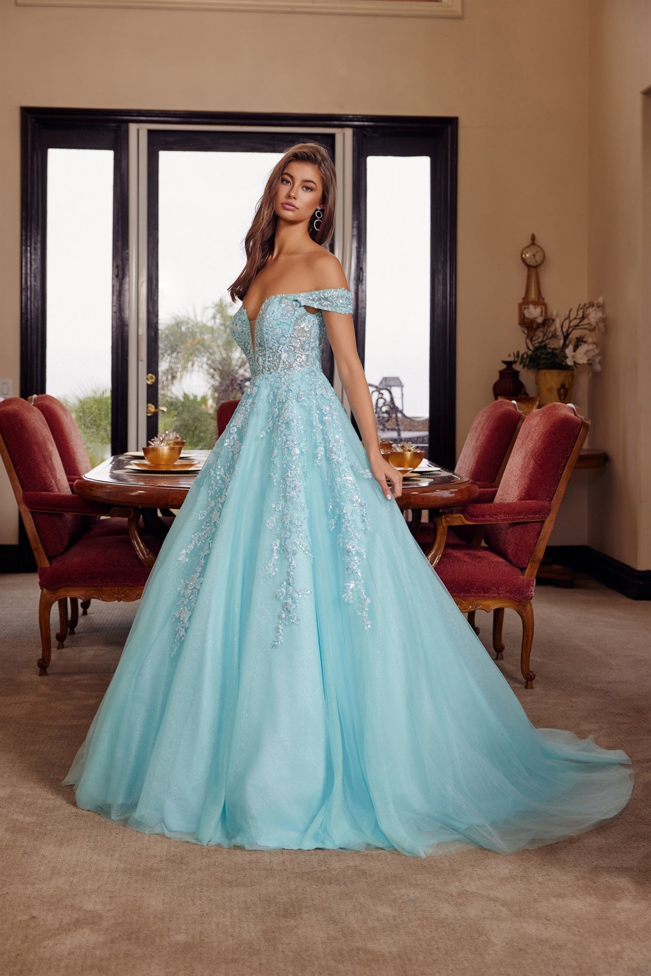 Nox Anabel's H1881 prom dress combines timeless elegance with contemporary allure. The off-the-shoulder silhouette frames the shoulders beautifully, while the sheer corset bodice creates a striking focal point with its plunging V-neckline. The flowing A-line skirt transitions into a graceful train, offering movement and drama on the dance floor. Crafted for those seeking a show-stopping entrance at prom or formal events, this dress balances sophistication with bold design details.

Sizes: 00-16

Colors: Aqu