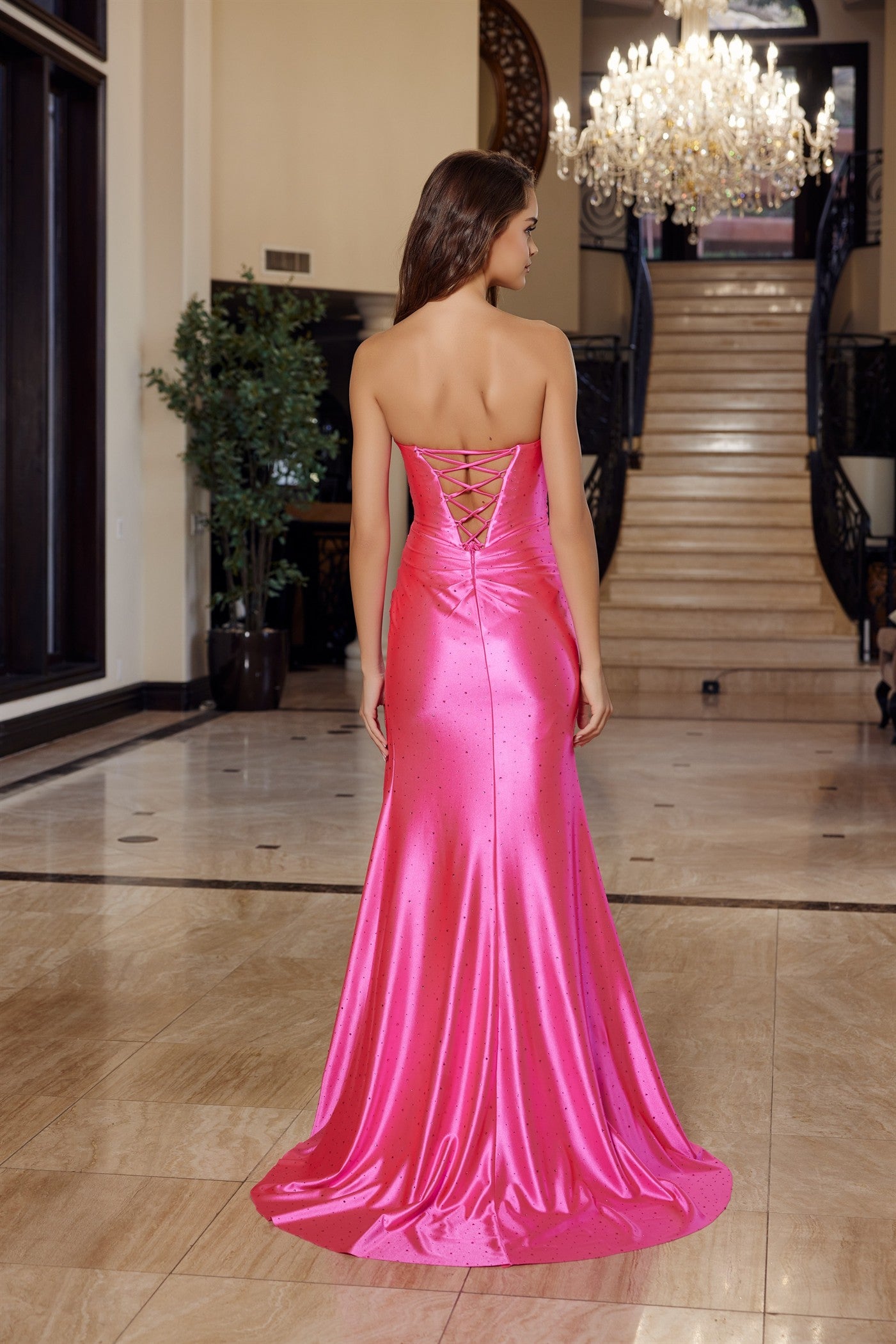 Nox Anabel's M1756 is a show-stopping prom dress designed for those who want to make an unforgettable entrance. The sweetheart neckline frames the shoulders beautifully, while the structured pleated corset bodice creates a flattering silhouette with elegant definition. Delicate crystal embellishments catch the light as you move, adding glamour and sophistication. The strapless design offers a modern, refined look, and the flowing satin fabric drapes luxuriously. A dramatic slit and train add movement and di