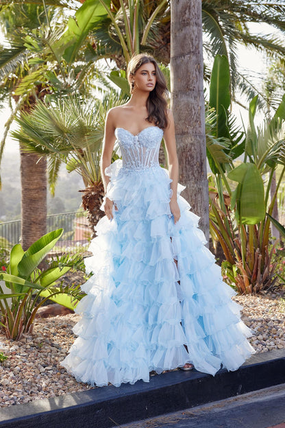 Elevate your prom night with the Nox Anabel R1688, a stunning strapless gown that commands attention. This sophisticated design features a sheer beaded lace corset bodice with a sweetheart neckline, creating an alluring silhouette. Delicate ruffles cascade down the skirt, while a dramatic slit and backless cut add modern edge and movement. The flowing train completes the look with timeless elegance. Perfect for those seeking a show-stopping statement piece that balances romance with contemporary style.

Siz