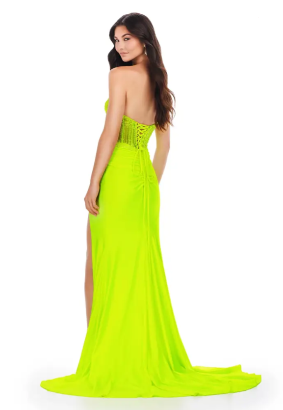 Ashley Lauren 11520 Long Fitted Jersey Maxi Slit Prom Dress Strapless Crystal Bodice This classic strapless jersey gown features a fully beaded corset bustier. The skirt features a left leg slit and ruched design.  Sizes: 00-24  Colors: Neon Green, Fuchsia, Royal, Coral  Sweetheart Neckline Beaded Bustier Lace Up Back Jersey Wrap Skirt