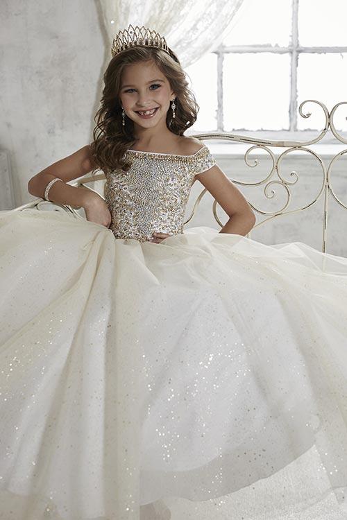 Get your little princess ready for the pageant stage with the Tiffany Princess 13457 Girls Long Pageant Dress. The beautiful off-the-shoulder style is adorned with Detailed beading that add a touch of sparkle to the bodice, while the fully gathered glitter tulle skirt adds a touch of shimmer. The lace-up back ensures a perfect fit for your little one. this dress is sure to make her shine on stage. 
