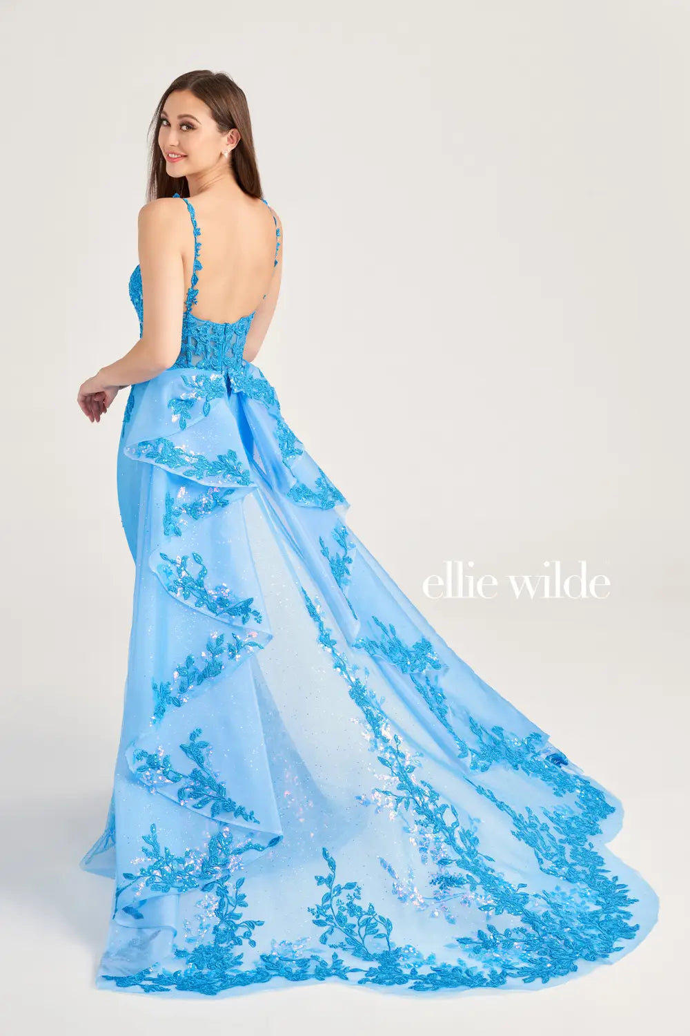 Be the center of attention in the Ellie Wilde EW35207 prom gown. Featuring a stunning lace sequin bodice with sheer corset detailing and a detachable side overskirt for added drama, this dress is perfect for pageants and prom. Turn heads and feel like a queen with this elegant and eye-catching dress.  Sizes: 00-16  Colors: Sage, Ocean Blue