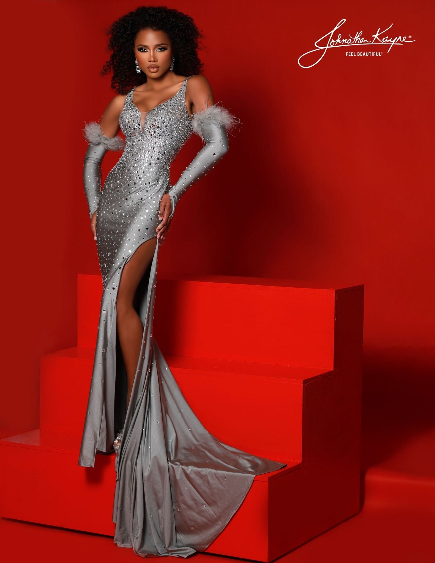 Be dazzling in this Johnathan Kayne 2720 evening gown. Its sleek crystal jersey bodice, Feathered trimmed glove sleeves, and graceful jersey skirt with a high slit create a silhouette that will turn heads wherever you go. Make your mark with this unforgettable style.   Sizes: 00,0,2,4,6,8,10,12,14,16  Colors: Black, Silver, Red, White , Royal
