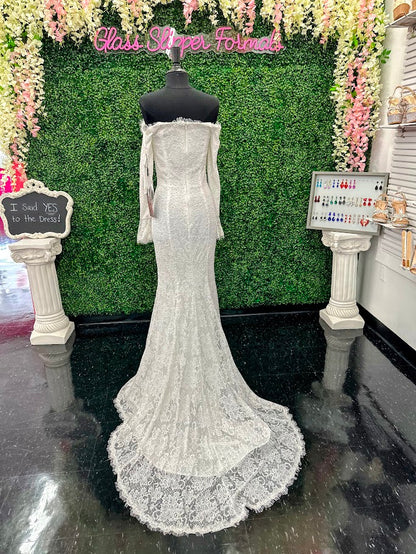This exquisite Johnathan Kayne gown in size 4 features a long, fitted silhouette crafted from delicate white lace. Designed with an off-the-shoulder neckline and long sleeves ending in elegant ruffle cuffs, it offers a refined and sophisticated look. The dress is adorned with AB crystals that add subtle sparkle, while the eyelash lace edges and flowing train enhance its graceful presence, making it an ideal choice for pageants or formal events.

Size: 4

Color: White