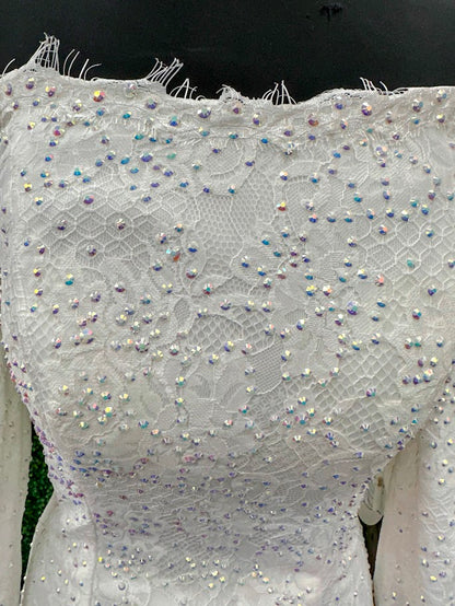 This exquisite Johnathan Kayne gown in size 4 features a long, fitted silhouette crafted from delicate white lace. Designed with an off-the-shoulder neckline and long sleeves ending in elegant ruffle cuffs, it offers a refined and sophisticated look. The dress is adorned with AB crystals that add subtle sparkle, while the eyelash lace edges and flowing train enhance its graceful presence, making it an ideal choice for pageants or formal events.

Size: 4

Color: White