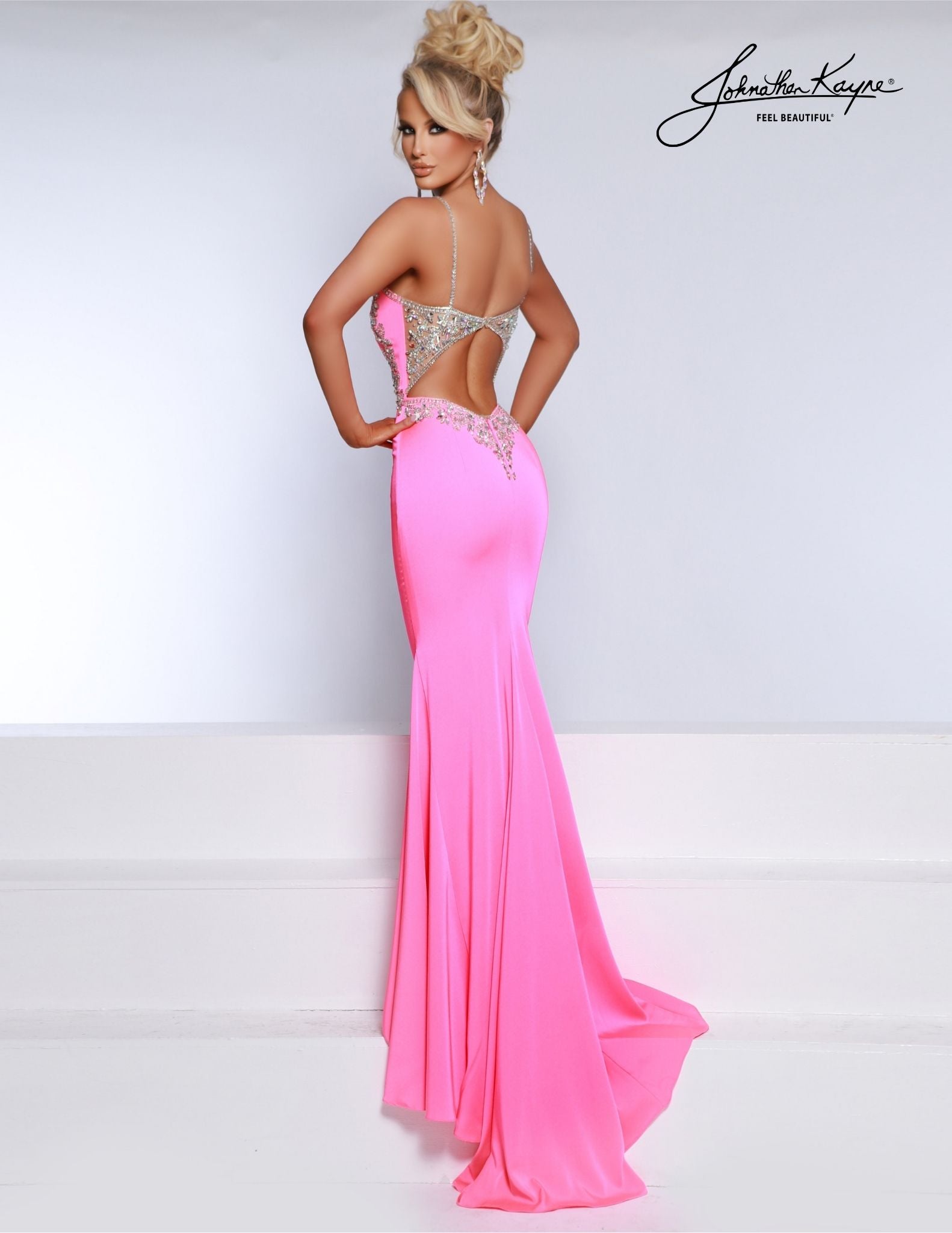 This Johnathan Kayne 2918 prom dress exudes elegance with its sheer backless design and intricate crystal embellishments. Made with high-quality crepe, this gown is perfect for formal events and pageants. Convey a sophisticated and luxurious look while feeling comfortable and confident. Embrace perfection in this stretch crepe gown. The sophisticated high-neckline alludes elegance while the fit and flare silhouette hugs all the curves in all the right places.  Sizes: 00-16  Colors: Taffy Pink, Black, White