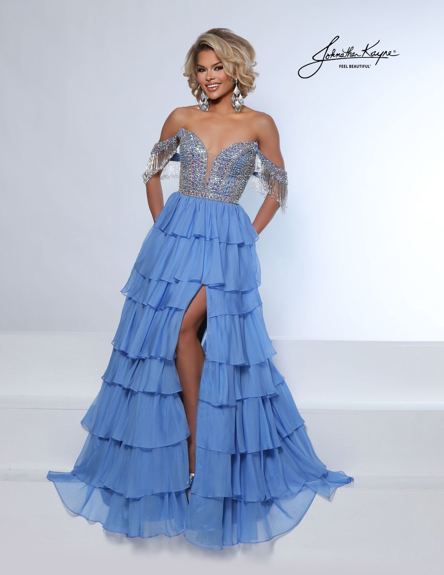 This elegant tiered poly chiffon gown by Johnathan Kayne features a fully beaded corset bodice with a plunging neckline, complemented by detachable off-the-shoulder fringe sleeves. The long layered A-line silhouette and high slit create a striking look, perfect for making a statement at homecoming, pageants, or prom.

Sizes: 00-16

Colors: Periwinkle, Royal, White