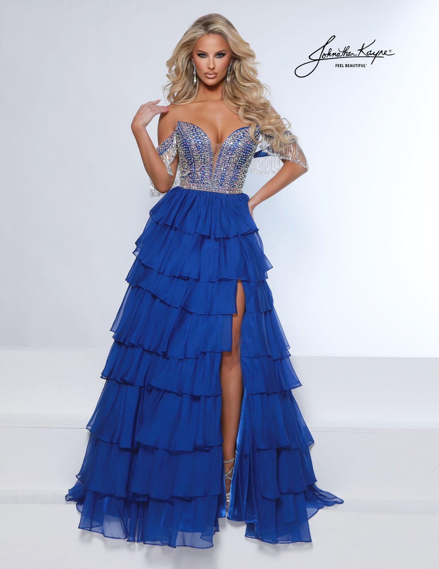 This elegant tiered poly chiffon gown by Johnathan Kayne features a fully beaded corset bodice with a plunging neckline, complemented by detachable off-the-shoulder fringe sleeves. The long layered A-line silhouette and high slit create a striking look, perfect for making a statement at homecoming, pageants, or prom.

Sizes: 00-16

Colors: Periwinkle, Royal, White
