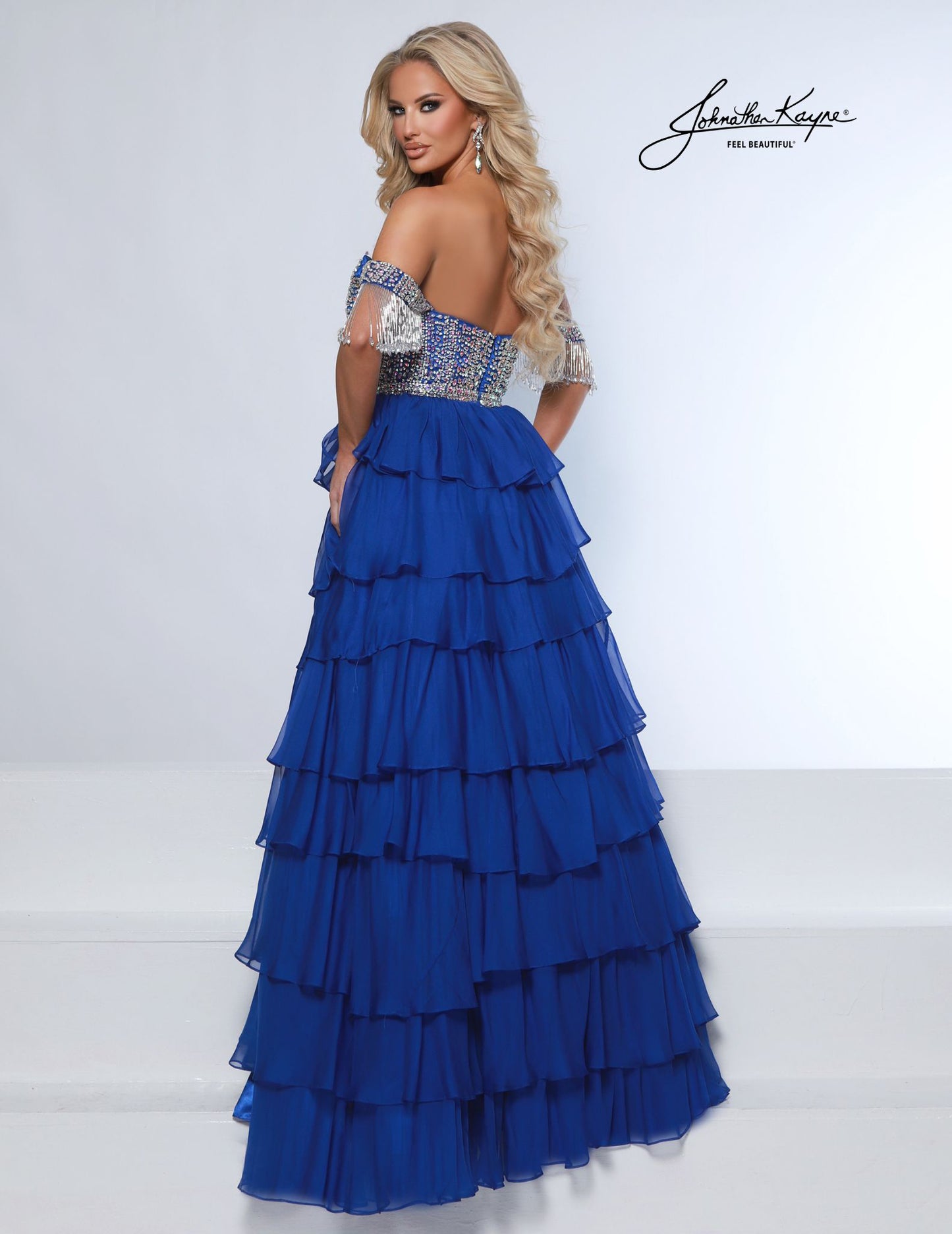 This elegant tiered poly chiffon gown by Johnathan Kayne features a fully beaded corset bodice with a plunging neckline, complemented by detachable off-the-shoulder fringe sleeves. The long layered A-line silhouette and high slit create a striking look, perfect for making a statement at homecoming, pageants, or prom.

Sizes: 00-16

Colors: Periwinkle, Royal, White