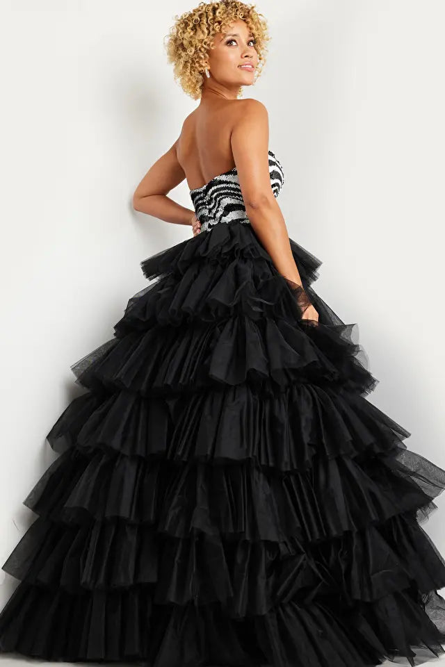 The Jovani 38360 is a striking formal gown designed to make a bold and fashionable statement at special occasions. It is crafted from tulle, a fabric known for its ethereal and lightweight quality, adding a touch of whimsy to the dress.  This ballgown-style dress features a voluminous and multi-layered full skirt that creates a dramatic and enchanting silhouette. The skirt is designed to make a grand entrance and captivate attention.