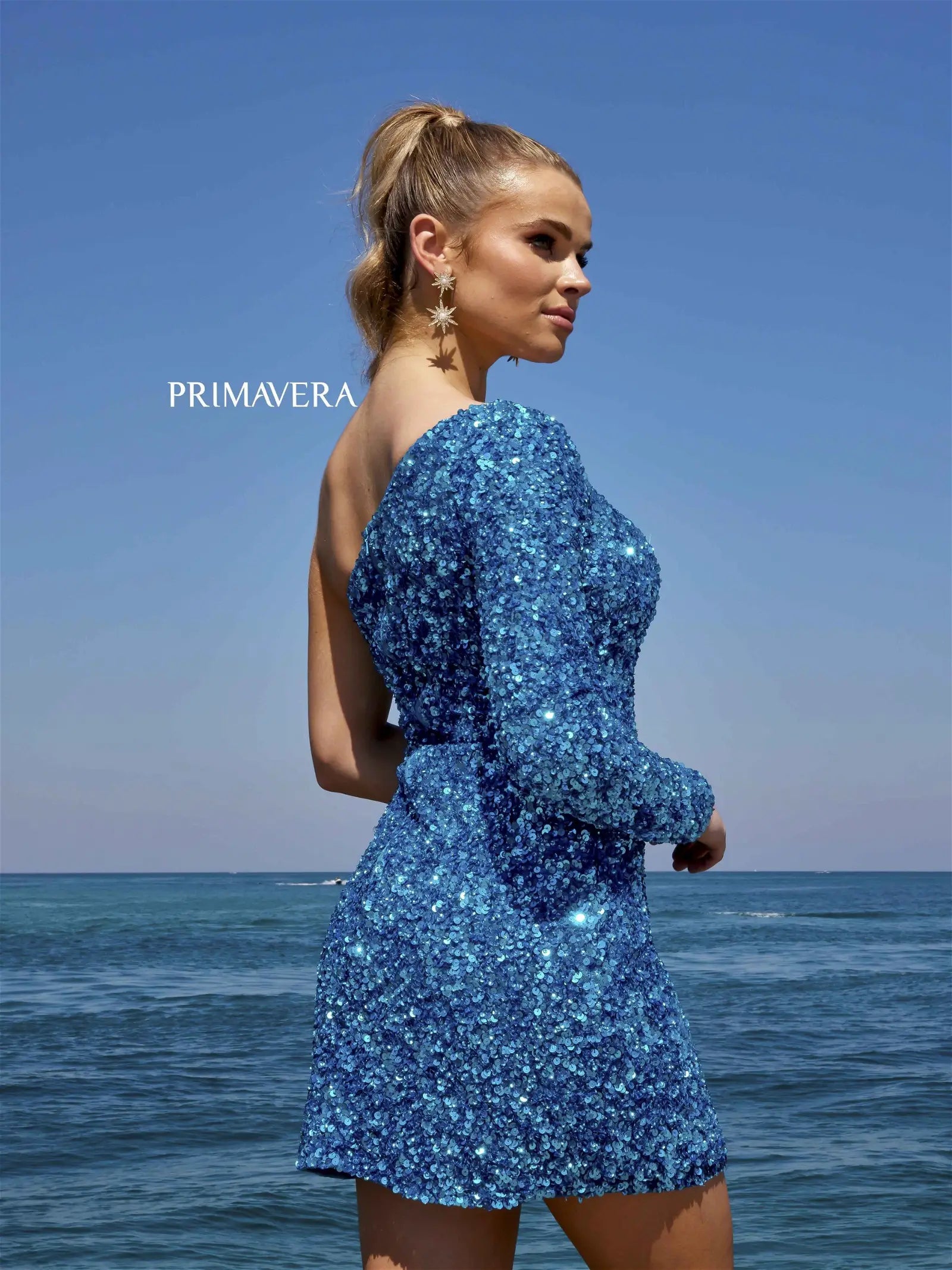 Look stunning for your homecoming with this Primavera Couture 3860 Short Homecoming dress. The fitted silhouette is intricately beaded with sequins and features a one-shoulder long sleeve and a maxi slit. Ready to make a grand entrance.