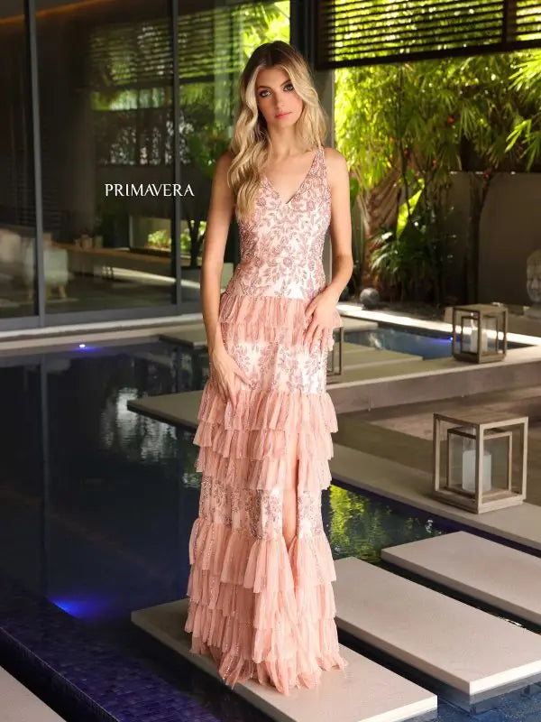 Elevate your formal look with the Primavera Couture 4106 Long Prom Dress. This stunning gown features an intricate sequin and beaded design, cascading layered ruffles, and a high slit for a touch of glamour. The fitted silhouette is perfect for showing off your figure, making this dress a statement piece for any special occasion.