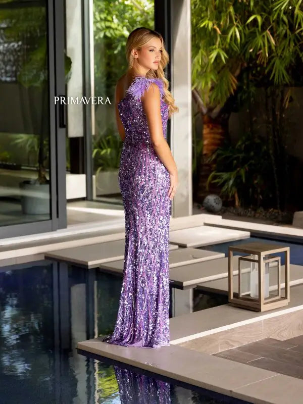 Experience elegance with the Primavera Couture 4169 dress. The one-shoulder, fitted body style is adorned with delicate sequins and feathers, making it a perfect choice for any formal occasion or pageant. With a high slit, you can show off your legs while feeling confident and glamorous.