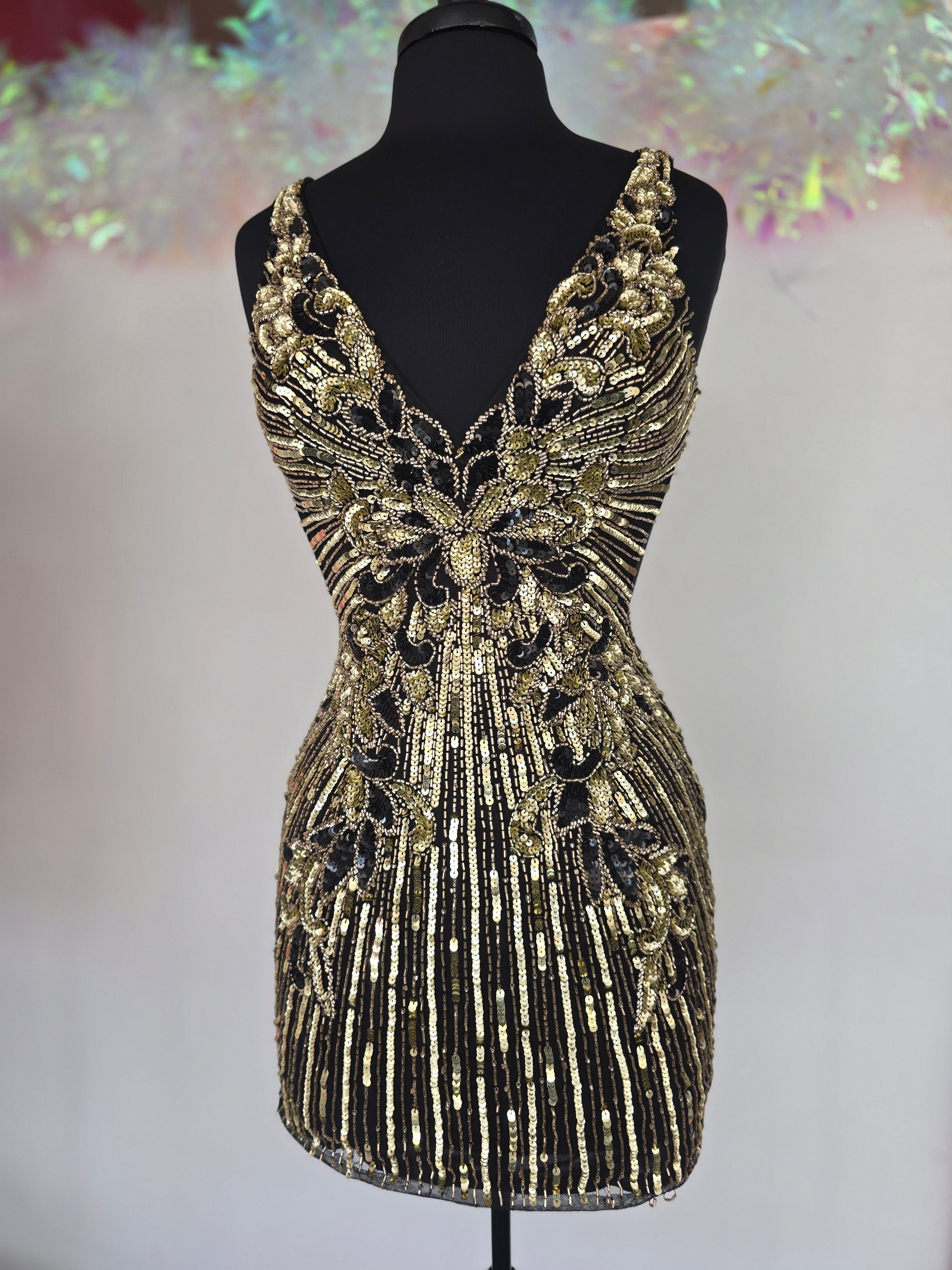 Make a stunning entrance with the Primavera Couture 4408, a short backless homecoming dress adorned with intricate beading and shimmering sequins. Its flattering V-neckline enhances your silhouette, while the backless design adds a touch of bold elegance. Perfect for cocktail events and special occasions, this gown combines glamour and comfort to help you feel confident and radiant all night long.

Sizes: 4

Colors: Black/Gold