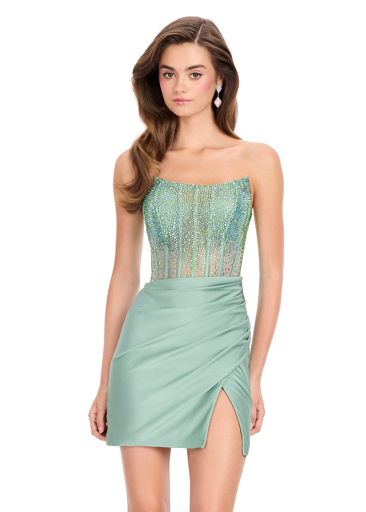 A woman modeling a strapless mini dress with a shimmering sequined bodice and a draped satin skirt in a sage green shade, set against a plain white background.
