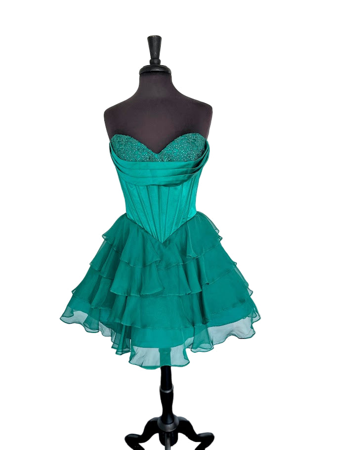 The Jovani 47763 combines elegance and youthful flair in a short cocktail dress designed for standout occasions like homecoming. Featuring a delicate lace-adorned cowl neckline and a structured corset bodice, it offers a flattering silhouette that enhances your figure. The ruffle flared skirt adds movement and a playful touch, balancing sophistication with charm. Ideal for events requiring both style and comfort, this dress ensures you make a memorable impression with expert craftsmanship and detail.

Sizes