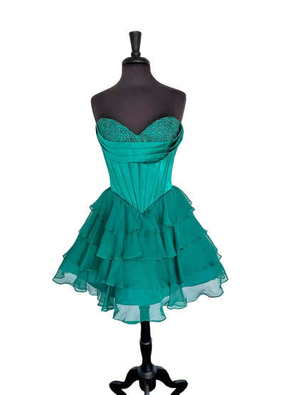 The Jovani 47763 combines elegance and youthful flair in a short cocktail dress designed for standout occasions like homecoming. Featuring a delicate lace-adorned cowl neckline and a structured corset bodice, it offers a flattering silhouette that enhances your figure. The ruffle flared skirt adds movement and a playful touch, balancing sophistication with charm. Ideal for events requiring both style and comfort, this dress ensures you make a memorable impression with expert craftsmanship and detail.

Sizes