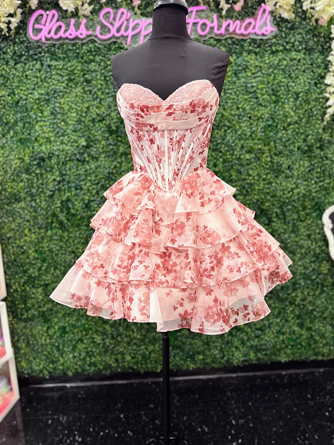 This Jovani 48771 homecoming dress features a flattering fit-and-flare silhouette with a corset bodice for structured support. The short, A-line skirt is enhanced with delicate ruffles and a vibrant floral print, creating a youthful yet elegant look. Crafted with lace accents, this cocktail dress balances sophistication and playful charm, making it an ideal choice for memorable celebrations and formal events.

Sizes: 00-24

Colors: Blue Print, Blush Print, Green Print