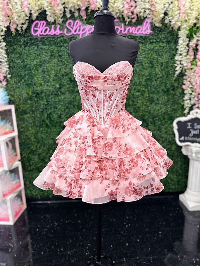 This Jovani 48771 homecoming dress features a flattering fit-and-flare silhouette with a corset bodice for structured support. The short, A-line skirt is enhanced with delicate ruffles and a vibrant floral print, creating a youthful yet elegant look. Crafted with lace accents, this cocktail dress balances sophistication and playful charm, making it an ideal choice for memorable celebrations and formal events.

Sizes: 00-24

Colors: Blue Print, Blush Print, Green Print