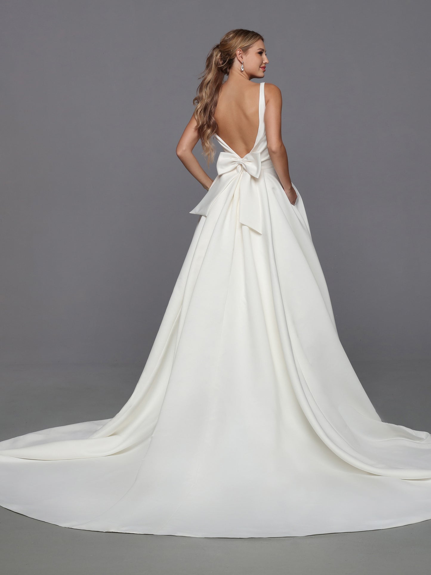 DaVinci Bridal 50766 A-Line Ballgown Satin Open Back Pockets Bow Train Wedding Gown. This feminine satin ball gown features lovely on-trend updates. The faux-wrap bodice has a waist-deep V-back accented with a removable oversized bow.