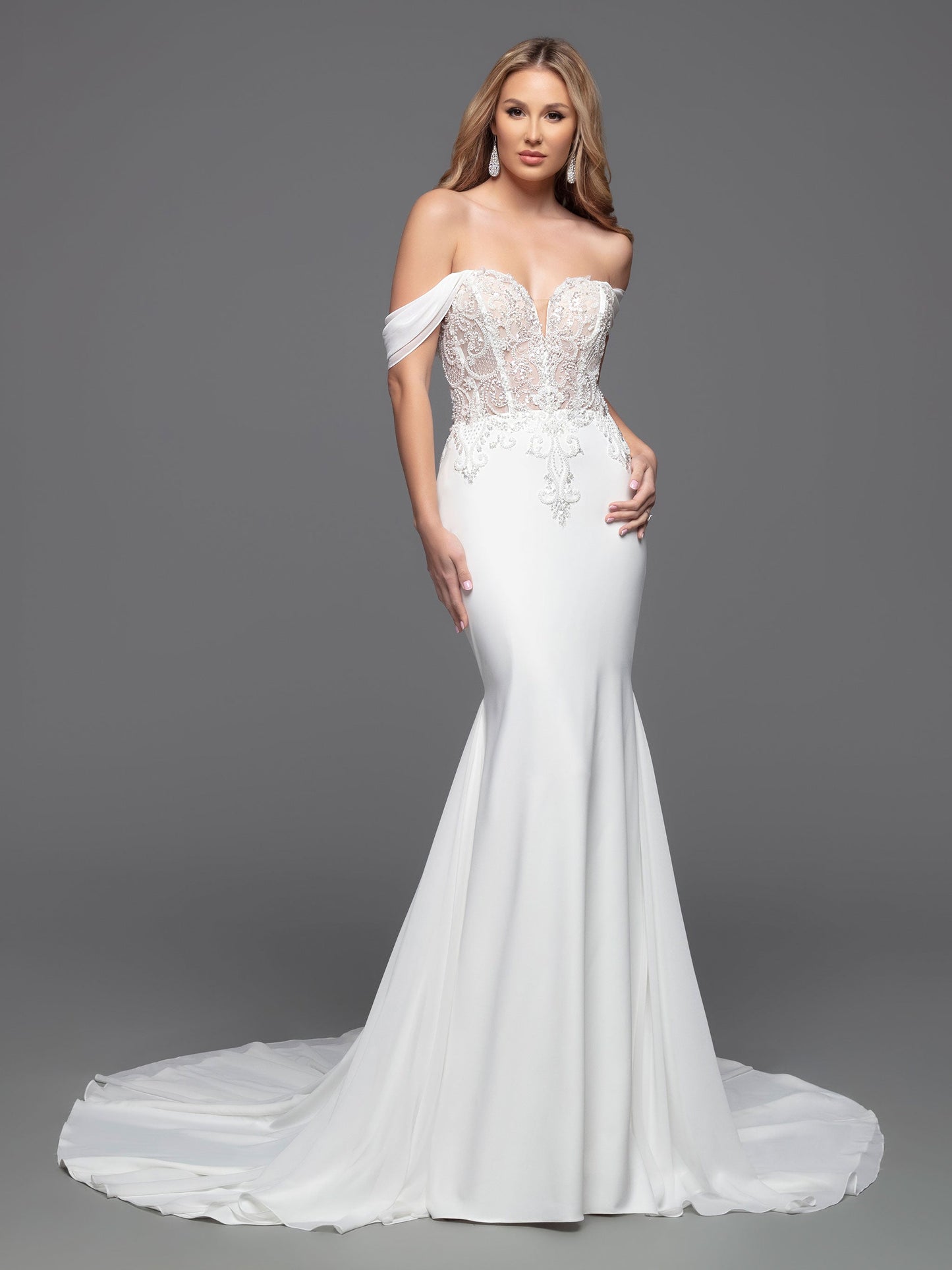 This Davinci Bridal 50803 Sheer Beaded Bodice wedding dress is a timeless choice for your special day. An elegant fit & flare silhouette with a corseted back, beaded appliques, and soft off-the-shoulder straps that flatter the neck and shoulders. The simple crepe skirt completes the classic look.  Sizes: 2-20  Colors: Ivory 