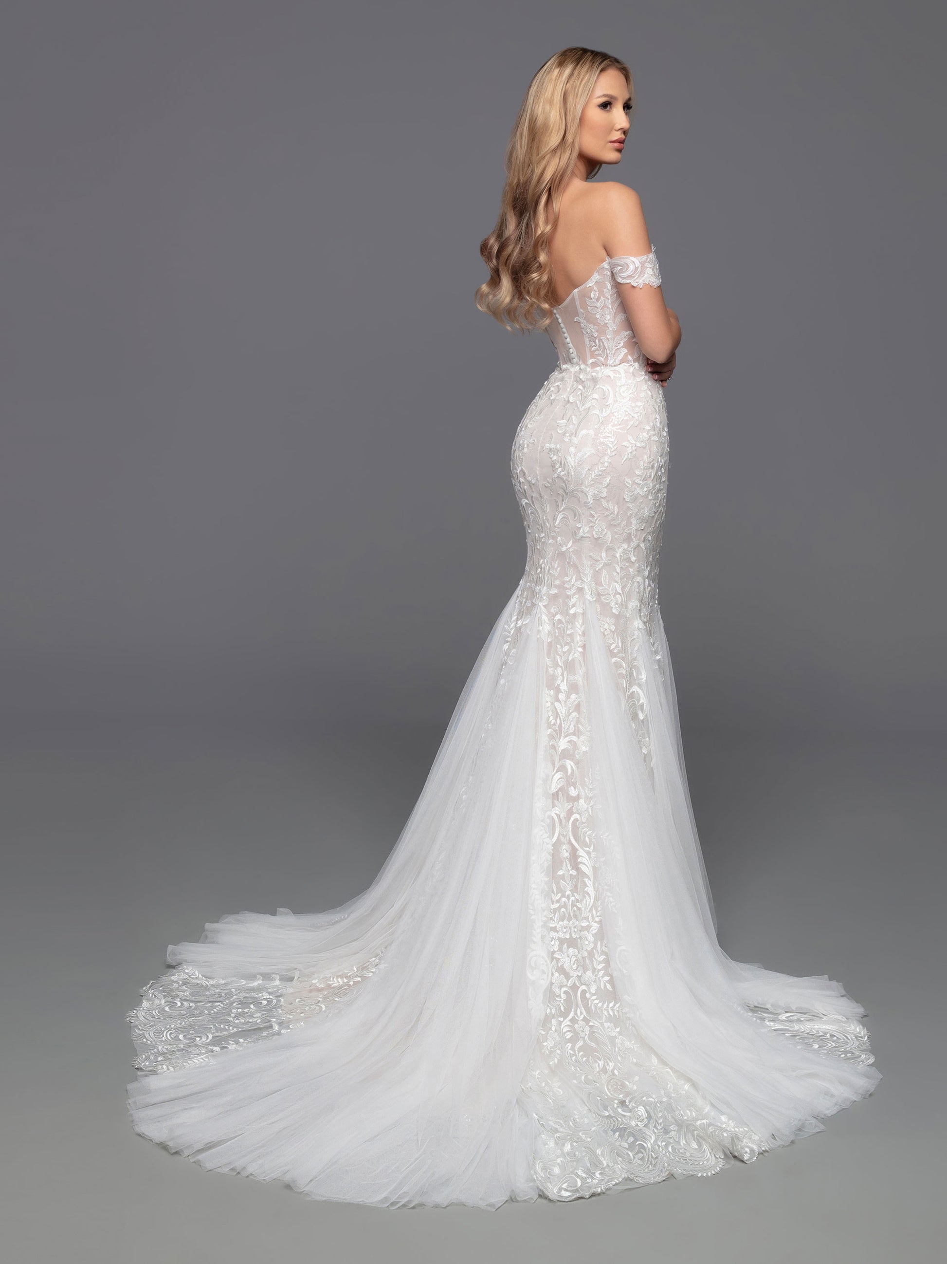 Look elegant and timeless in the Davinci Bridal 50812 Shimmer Lace Mermaid Wedding Dress. This luxurious gown features a lace bodice lined with sheer, off-the-shoulder sleeves, a sheer back, and covered buttons. Soft tulle, vertical lace panels and sheer lace panels enhance the design of this beautiful fit & flare gown, and a chapel train completes the look.  Sizes: 2-20  Colors: Ivory/Ivory, Ivory/Nude