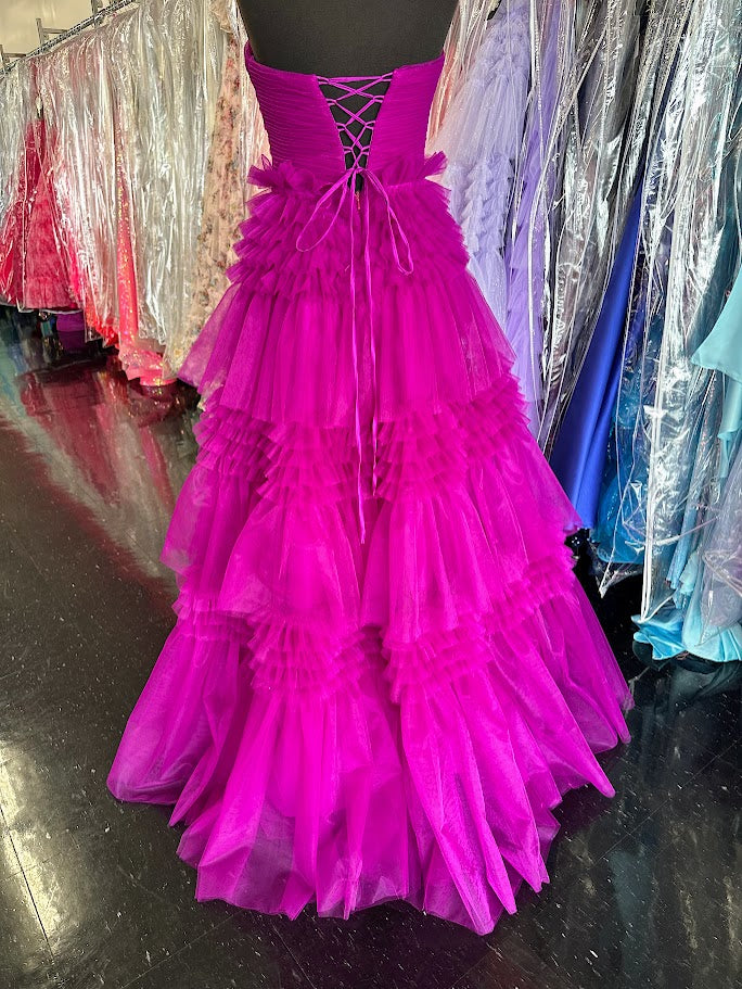Elevate your evening with the Nina Canacci 5305 prom dress, featuring a flowing A-line silhouette crafted from layered magenta tulle. The long pleated skirt adds graceful movement, while the corset bodice offers a flattering fit and elegant structure. A daring maxi slit enhances allure, making this ballgown perfect for making a sophisticated statement at any formal event.

Size: 4

Color: Magenta