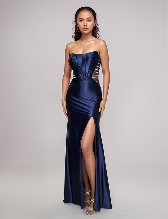Make a bold entrance with the Nina Canacci 5307 gown. This long, fitted strapless dress features a seductive corset silhouette with sheer panels that hint at allure, while the satin fabric drapes smoothly across your figure. A daring thigh-high slit adds movement and confidence, perfect for unforgettable evenings and prom night glamour.

Size: 0-12

Color: Burgundy, Navy, Emerald